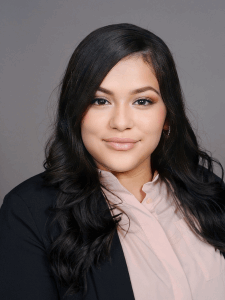 Professional photo of a female with long black hair, smiling, wearing a light pink shirt and a black blazer