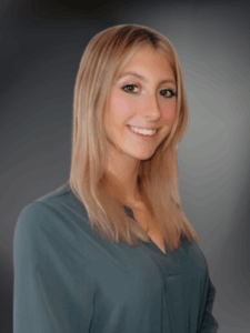 Professional photo of a female with medium length blonde smiling and wearing a green collared shit