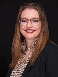 Professional photo of Kelly. Kellyis a middle-aged woman with reddish brown hair. She is dressed in business professional attire.