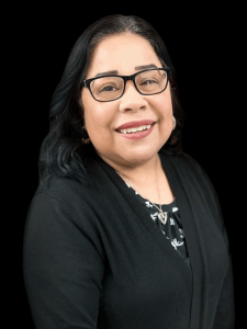 Professional photo of a female receptionist with black hair wearing a black and white blouse with a black cardigan