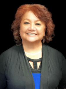 Professional photo of a female clinical specialist with red hair wearing a blue and black top with a black cardigan 