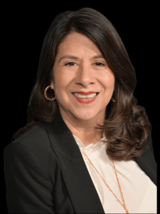 Professional photo of a female franchise co-owner with black hair wearing a white top with a black blazer and gold necklace