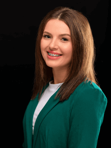 Professional photo of Aubrey. She is a young woman with dark hair. She is dressed in business professional clothes. 