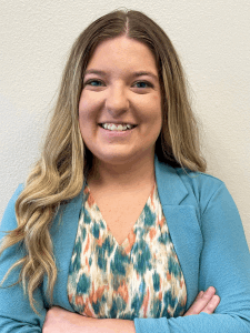 Professional photo of a young female light industrial recruiter with long blonde-brown hair wearing a colorful top and light blue blazer