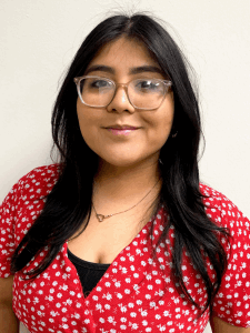 Professional photo of a young female recruiter with dark hair wearing glasses and a red dress