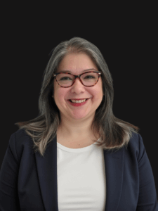 Professional photo of Julia. Julia is a middle-aged woman with black and silver hair. She is dressed in business professional attire.