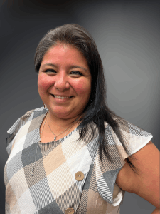 Professional photo of a young female Payroll Specialist with dark hair and a tan and grey plaid shirt